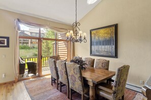 Un coin repas avec une table en bois, des chaises à motifs, un lustre et un tableau au mur.
