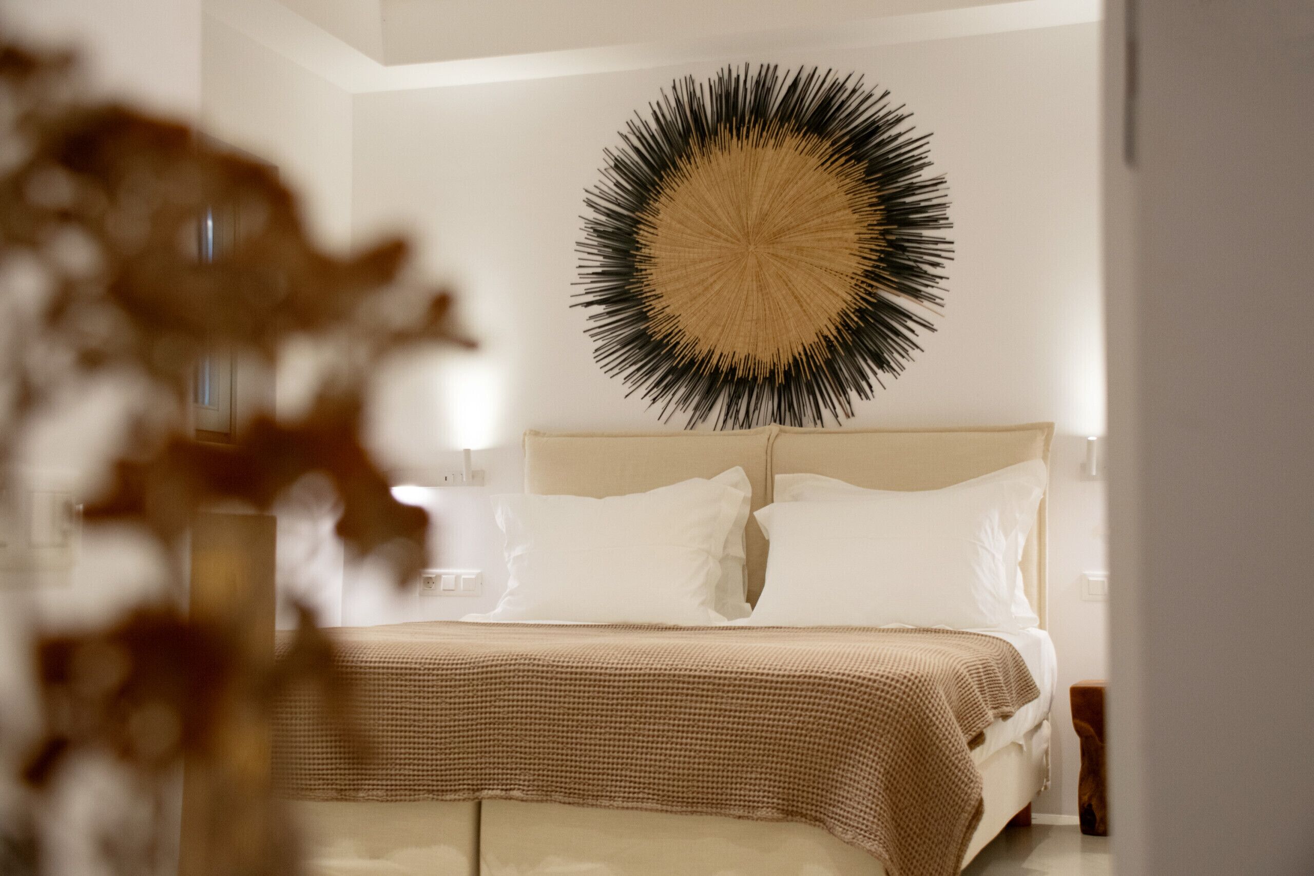 Ein modernes Schlafzimmer mit einem großen Bett, einer runden Wanddekoration und einem Nachttisch aus Holz.