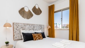 A modern hotel room with a large bed, two wall-mounted lamps, a decorative headboard, and a window with curtains. - Nala Apartment, Wifi, Algarve !new! (Faro)