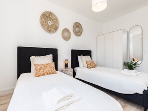 Quarto de hotel com duas camas, um espelho grande e arte decorativa em tecido na parede.