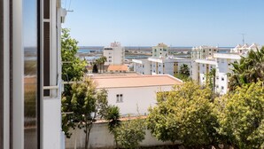 A coastal residential area with white buildings, some with red roofs, and a clear view of the sea in the background. - Nala Apartment, Wifi, Algarve !new! (Faro)