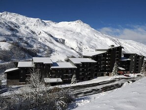 Une montagne enneigée, avec un ensemble de bâtiments au premier plan.