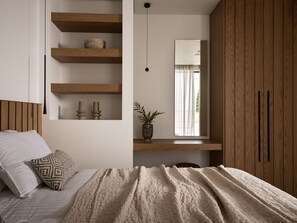 A bedroom with a bed, a bedside table, a mirror, a window with curtains, and built-in wooden shelves. - Anthis Luxury Villa (Zakynthos)