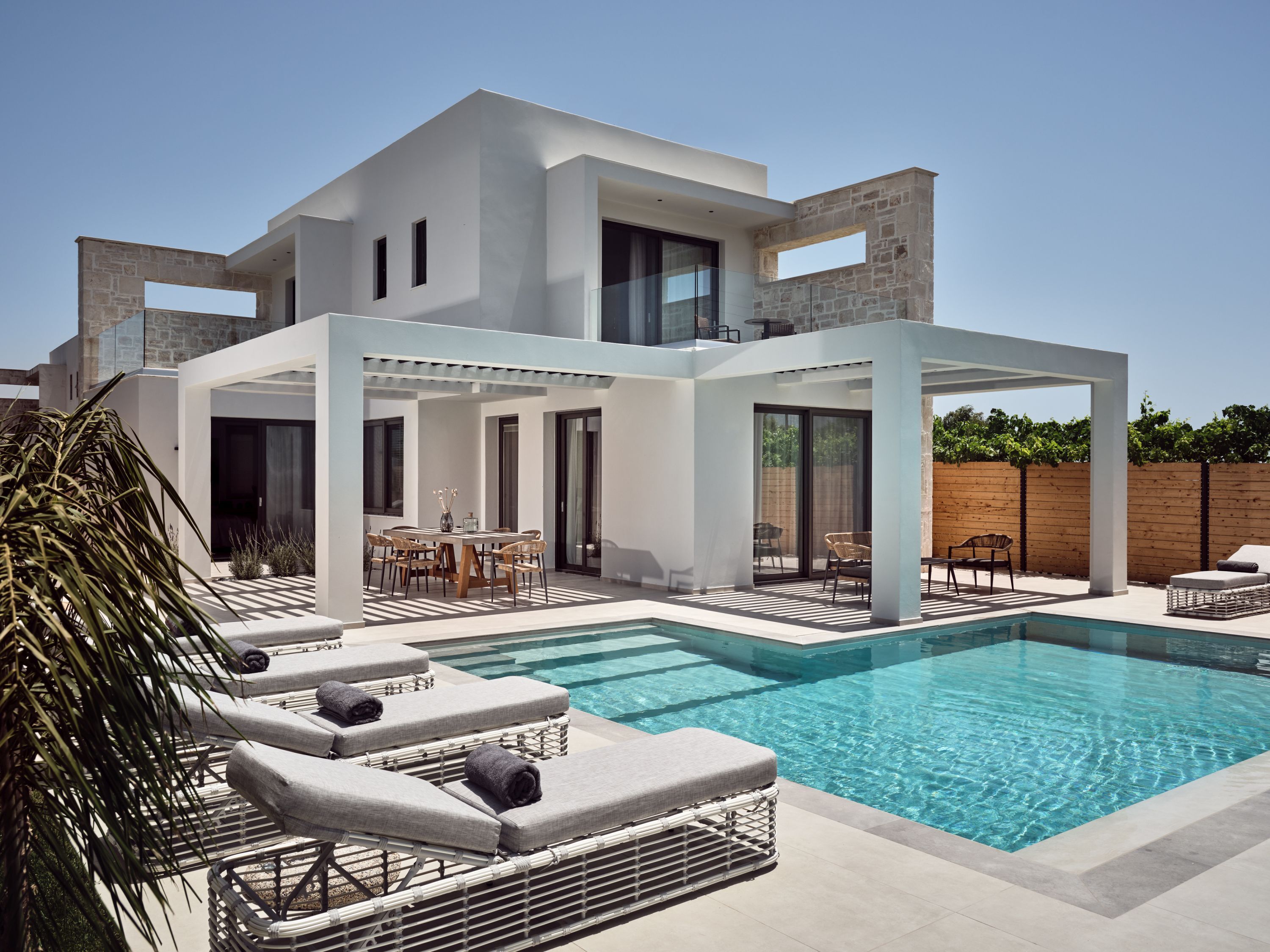 A modern house with a swimming pool, outdoor seating, and a pergola.