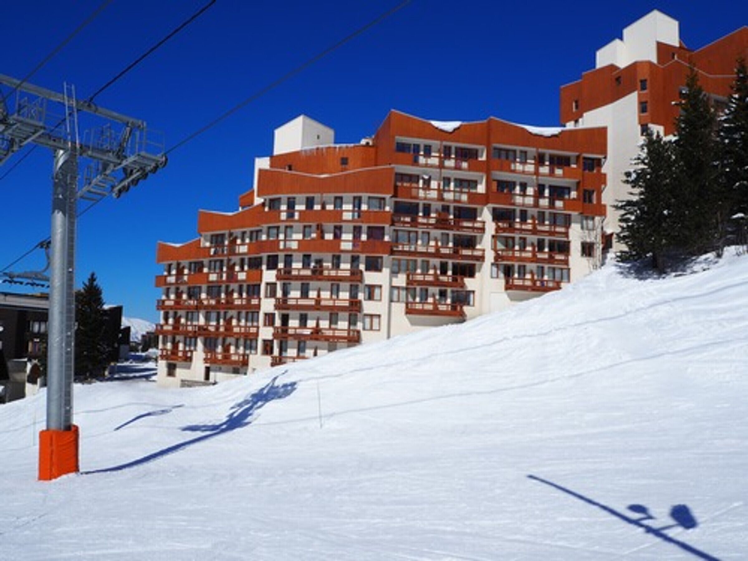 Un hotel a più piani con balconi e una pista da sci sullo sfondo.