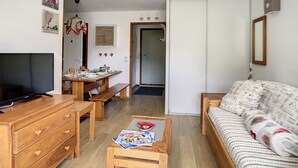 Un accogliente soggiorno con televisione, mobili in legno, un tavolo da pranzo e un divano.
