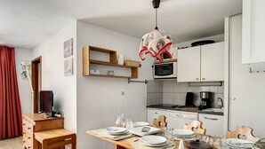 Una cucina compatta con mobili bianchi, un forno a microonde e una macchina per il caffè. Un tavolo da pranzo apparecchiato con piatti e posate.