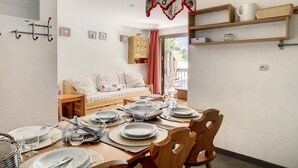 Zona pranzo con tavolo in legno apparecchiato per quattro persone, una poltrona e una lampada a sospensione.