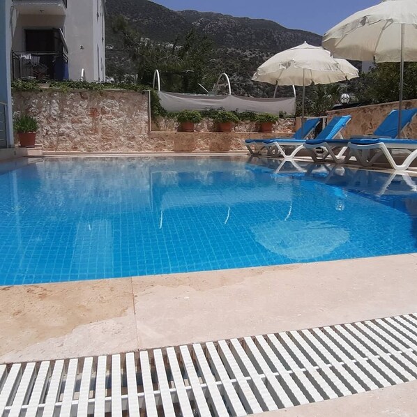 En säsongsöppen utomhuspool, parasoller och solstolar