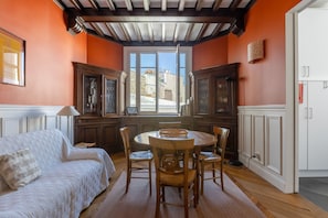 Relax in this traditional room with a round dining table, sofa, and large window offering a view of the surrounding buildings.