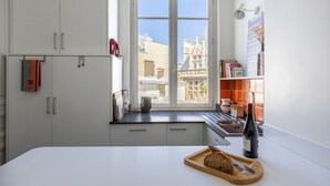 Una cocina moderna con un ventanal grande, armarios blancos y una tabla de madera con pan.
