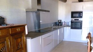 A modern kitchen with white cabinetry, stainless steel appliances, and a wooden cabinet with drawers.