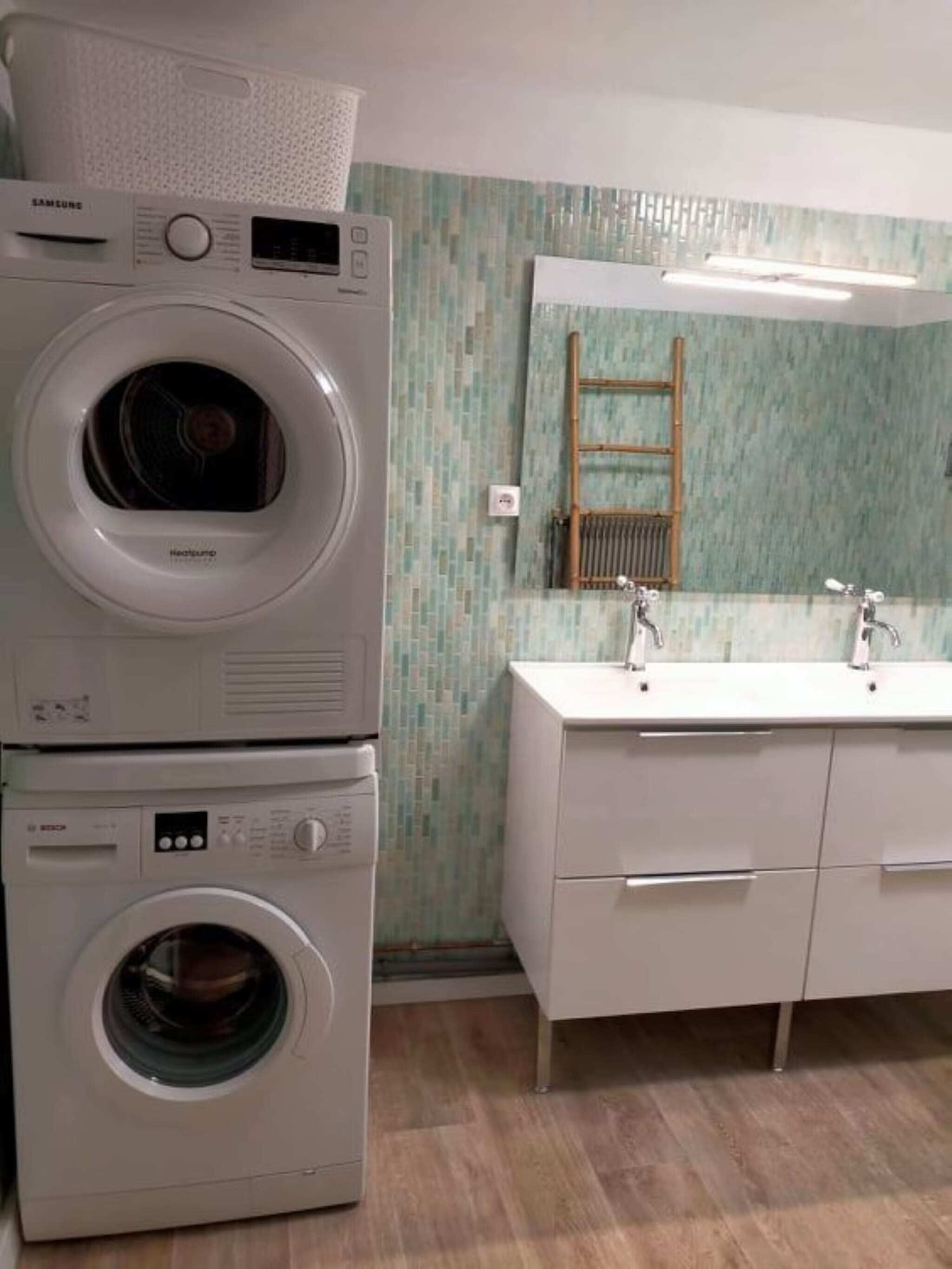 A laundry area with stacked washing machines and a modern bathroom with a mirror and sink.