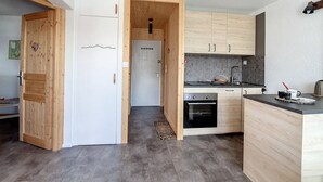 A compact kitchen with wooden cabinets, a built-in oven, and a small countertop. - Modern 3-room apartment, ski-in/ski-out, balcony, exceptional view (Les Menuires)