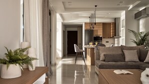 A modern living room with a sofa, coffee table, and a dining area with chairs. - Anthis Luxury Villas - 3 Bedroom Villas with Private Pool (Zakynthos)