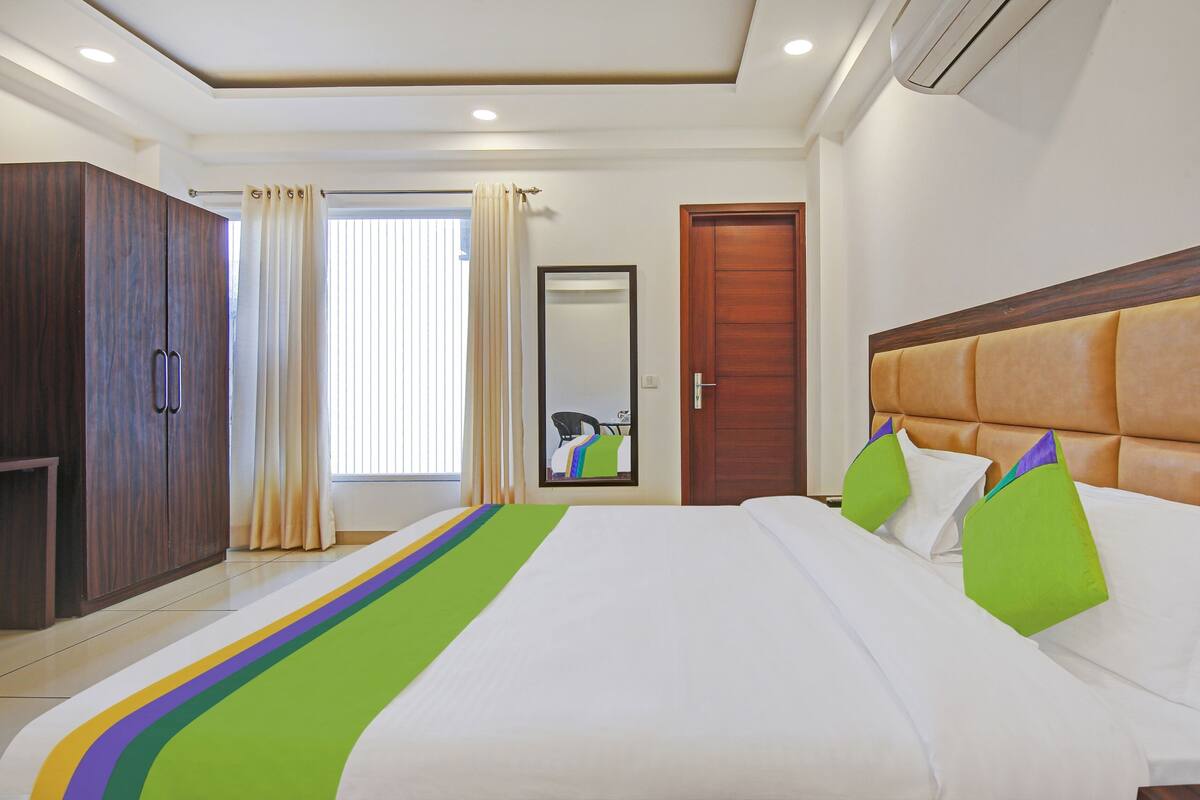 Quarto de hotel com cama, guarda-roupa, espelho e porta.