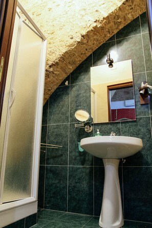 A bathroom with a white pedestal sink, a mirror, and a shower enclosure. - hotel Concordia s.n.c. (Crotone)