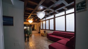 A room with a red sofa, a chandelier, and a large window with a view. - hotel Concordia s.n.c. (Crotone)