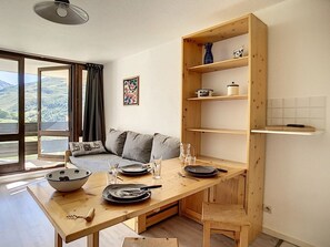 Een moderne keuken met houten kastjes, een eettafel gedekt voor twee personen en uitzicht op de omgeving door grote ramen.