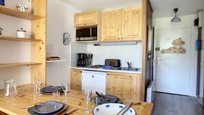 Una cocina compacta con armarios de madera, microondas, cafetera y refrigerador pequeño.