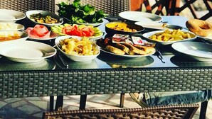 Una mesa dispuesta con varios platos en un balcón con vista al mar.