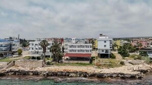 Un pueblo costero con edificios de varios pisos, un litoral rocoso y una vista despejada del mar.