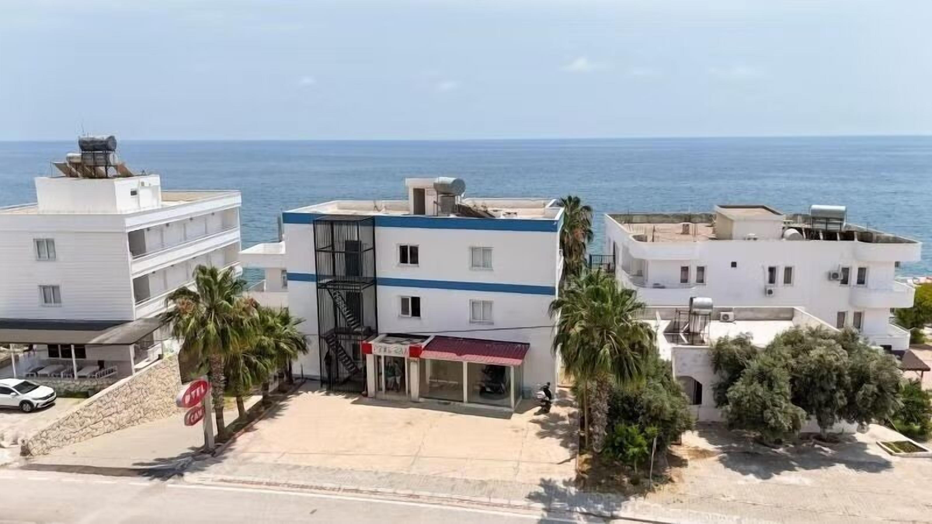 A coastal hotel with multiple floors, a visible staircase, and a view of the sea.