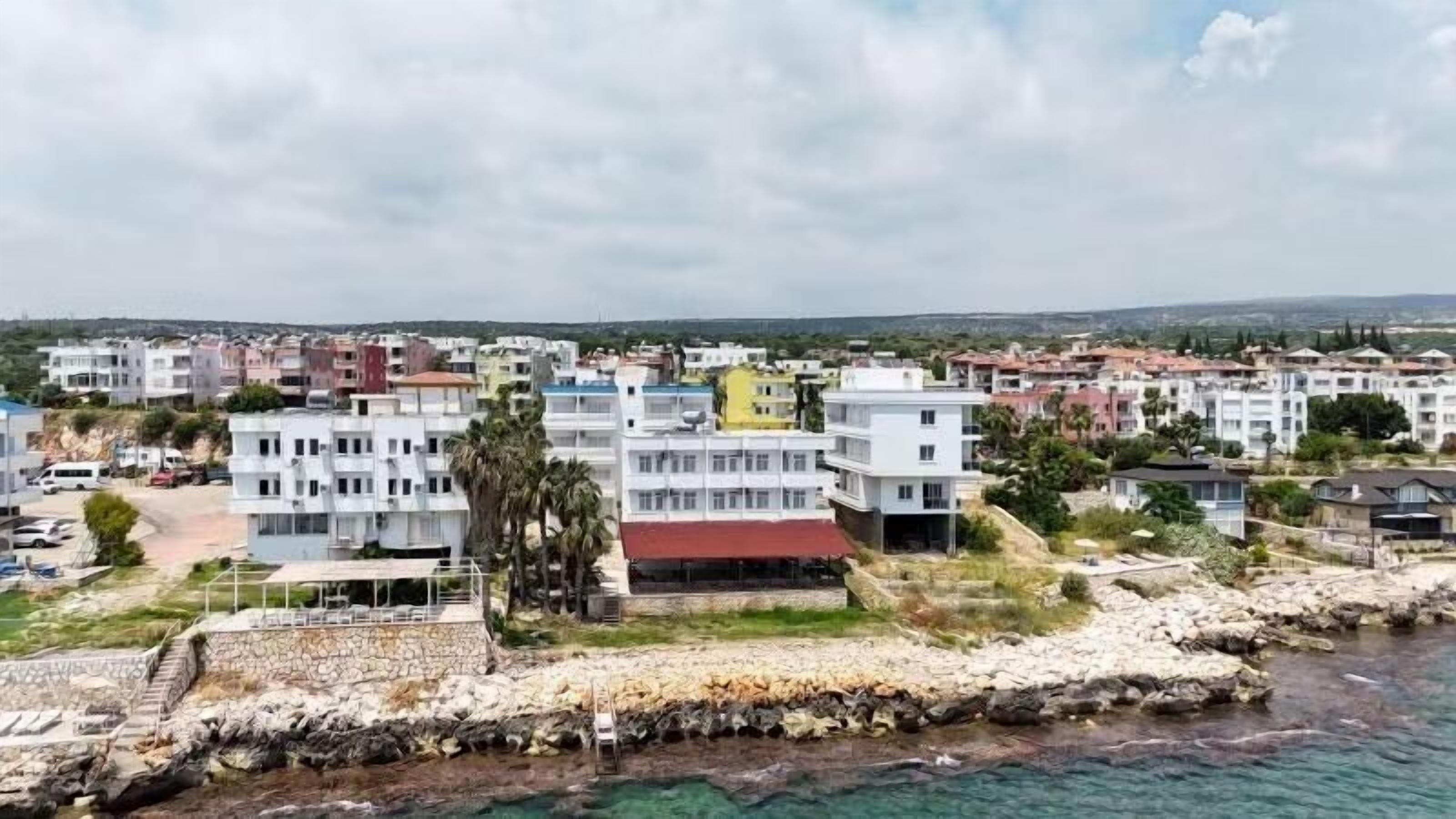 Un pueblo costero con edificios cerca del agua, un litoral rocoso y un cielo despejado.