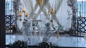 Decoración para boda al aire libre con escenario, arreglos florales y vista al mar.