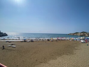 Ein Strand mit blauem Himmel, ruhiger See und felsigen Klippen.