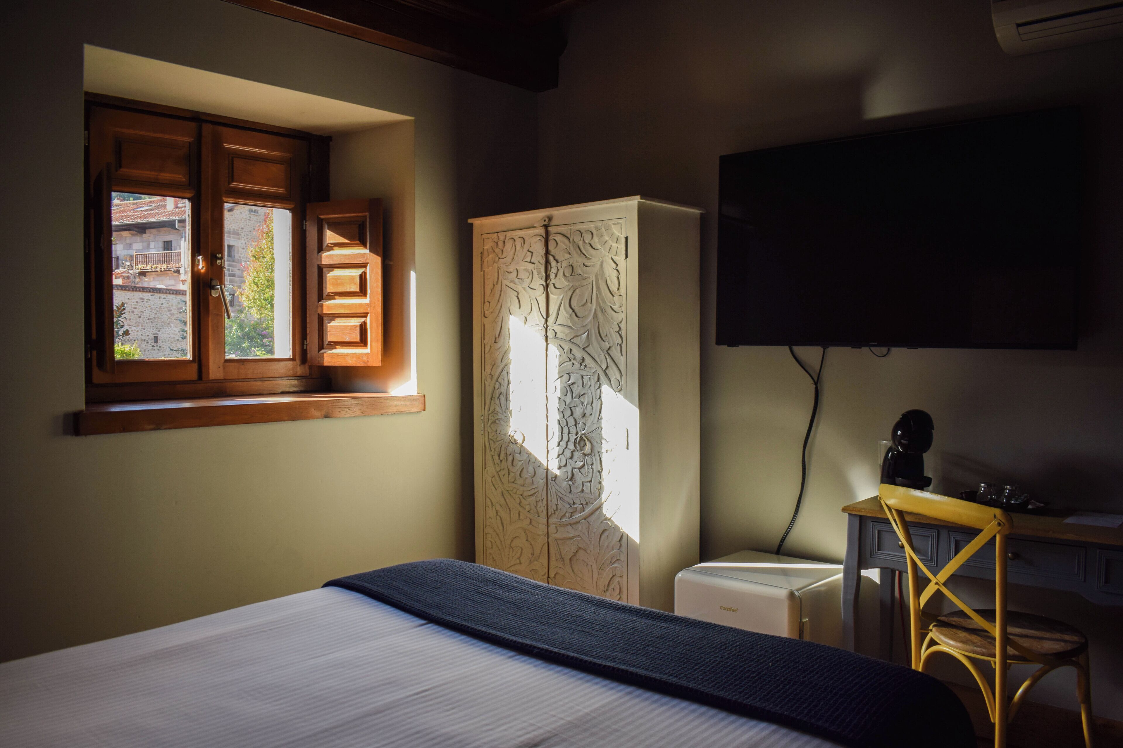 Une chambre à coucher comprenant un lit, une armoire, un bureau avec une chaise et un téléviseur fixé au mur.