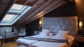 A bedroom with a large bed, a chair, a desk, and a skylight. - Casona De La Pinta (Cartes)