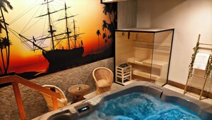 A hot tub with a wooden deck, wicker chairs, and a small table. - Casona De La Pinta (Cartes)