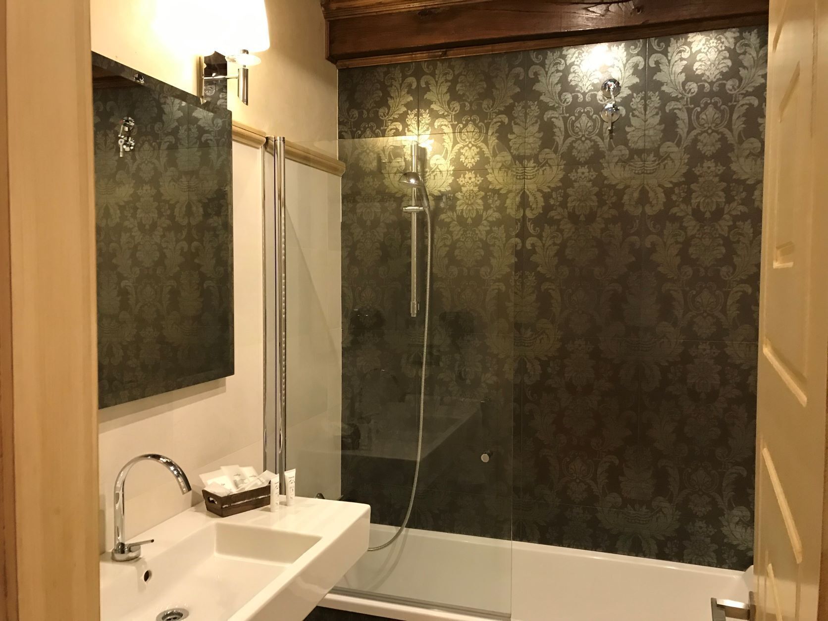 A bathroom with a glass-enclosed shower, a white sink, and a mirror.
