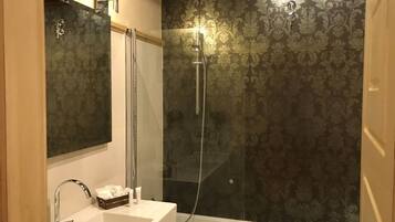 A bathroom with a glass-enclosed shower, a white sink, and a mirror.