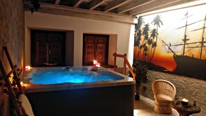 A hot tub with a sunset mural, wooden doors, and a wicker chair. - Casona De La Pinta (Cartes)
