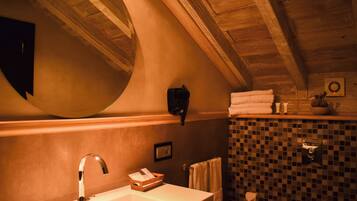 A bathroom with a wooden ceiling, a sink, a mirror, a towel rack, and a tiled wall.