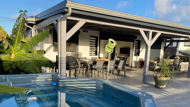 A pool area with a covered patio, outdoor seating, and a trash can. - T4 Sainte Anne - Fonds Thezan (Sainte-Anne)