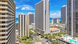 A high-rise hotel with multiple floors, a swimming pool, and a view of the ocean.