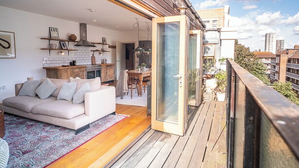A modern apartment with a balcony, a kitchen, and a living area with a sofa and a dining table.