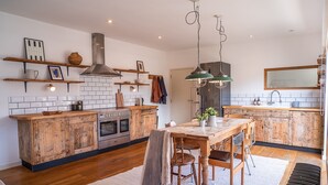 A modern kitchen with wooden cabinets, a central island, and a dining area with a table and chairs.