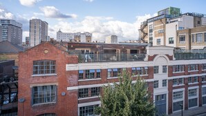 A multi-story building with a mix of brick and modern glass facades, featuring balconies and large windows.
