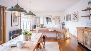 A dining area with a wooden table, chairs, and hanging pendant lights.