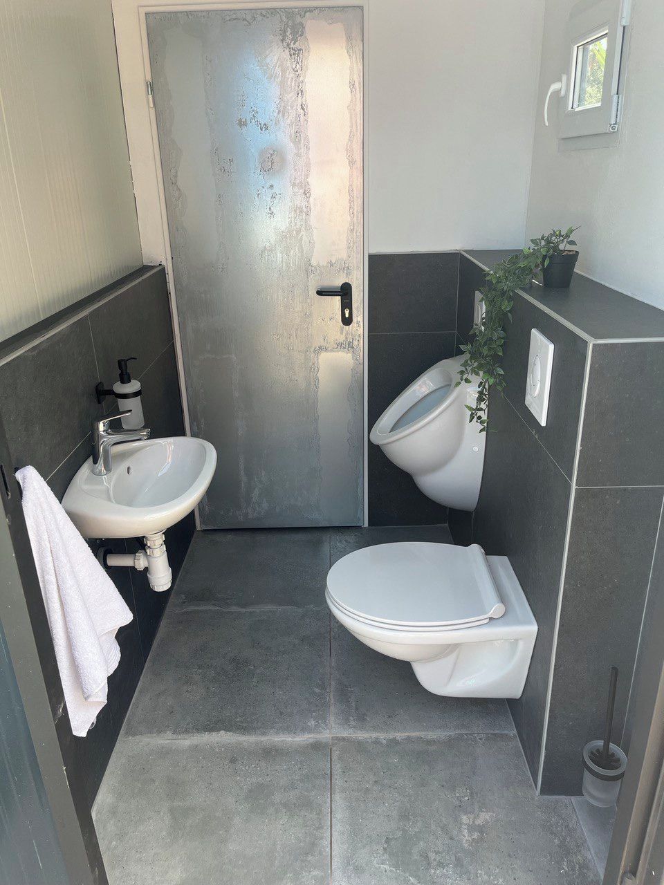 A compact bathroom with a white sink, a toilet, and a door.