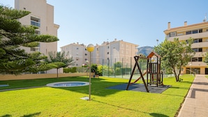 Un quartier résidentiel doté d’une pelouse verdoyante, d’une aire de jeux et d’une piscine.