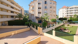 Un hôtel à plusieurs étages doté de balcons, d’une piscine et de jardins aménagés.