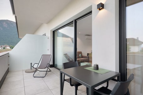 A balcony with a table and chairs, a chair with a cushion, and a view of a mountain.. Bike Apartments Curti "Waldgrün" with Sun Terrace & Alpine Views