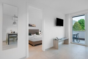 Ein modernes Schlafzimmer mit Bett, Nachttisch und an der Wand montiertem Fernseher.
