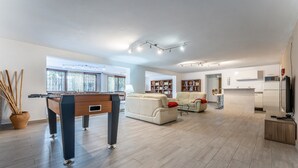 Ein geräumiger Wohnbereich mit Billardtisch, Sofas, Kamin und Küchenzeile.