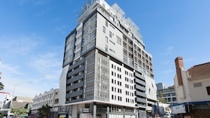 Een meerlaags gebouw met een modern architectuurontwerp, met een opvallende ingang en diverse balkons.